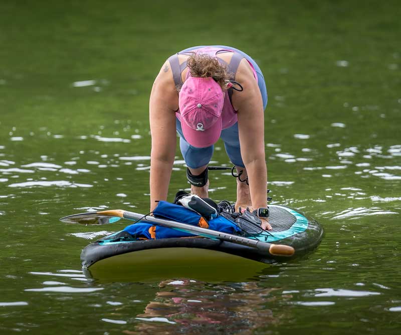 woman doing SUP yoga on a paddleboard