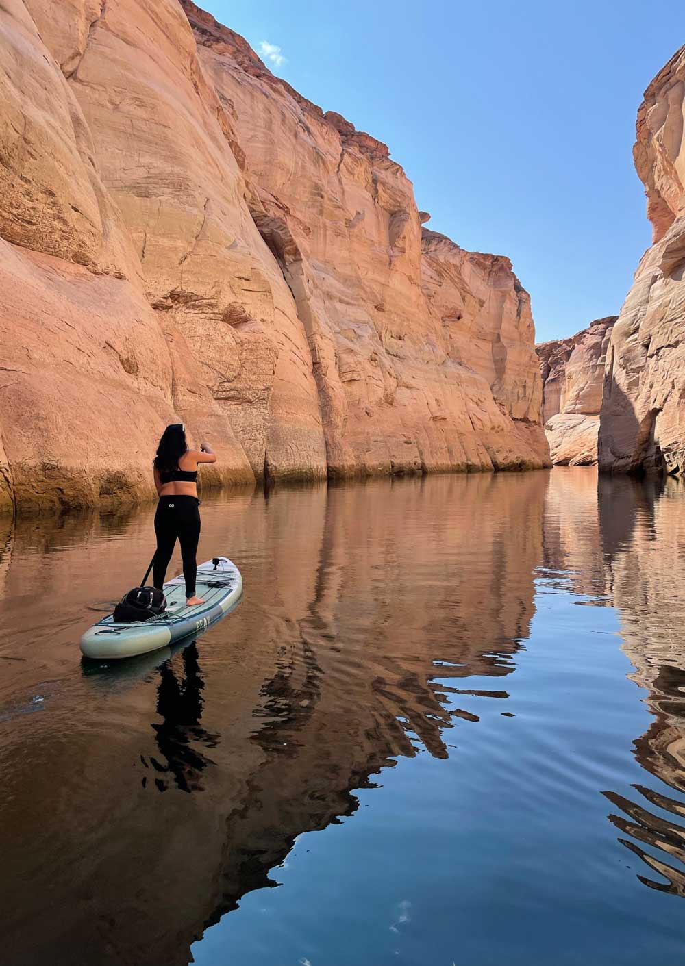 woman standing on paddleboard in scenic river on retreat for SUP yoga