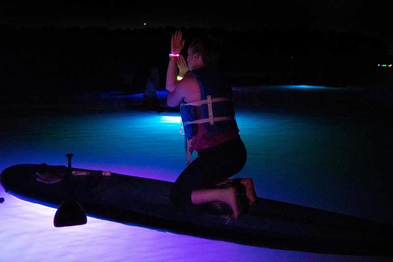 woman taking a night SUP yoga class